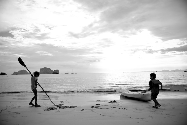 Kids playing with canoes on Pranang Beach Thailand