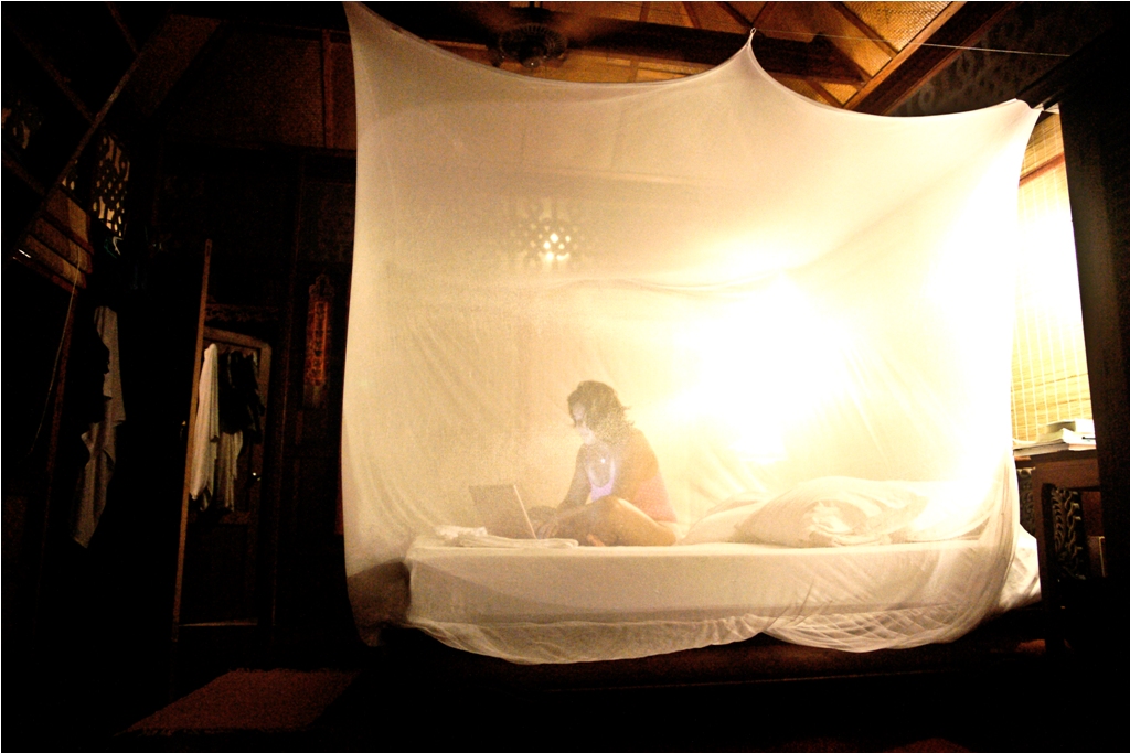 Me Ra Koh writing in Thailand under mosquito net